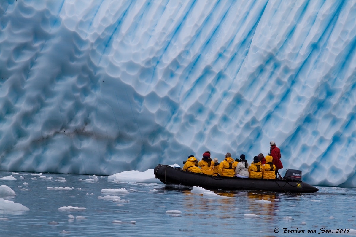 A group of zodiac cruisers admire the Antarctic Iceberg as close as possible.  The scale of the huge ice in comparison to the boat gives some perspective to the size of these icebergs.