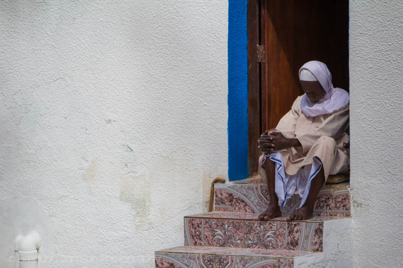 An Omani man sleeping on his steps in the heat of the day.